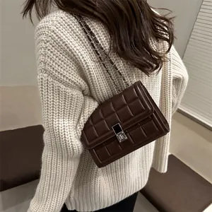 Quilted flap crossbody bag in dark brown leather with metal chain strap on model