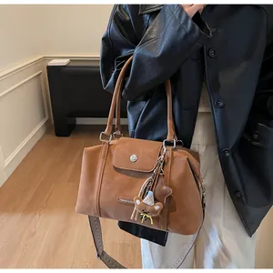 Close-up of brown matte crossbody bag with wide geometric strap and bear charm