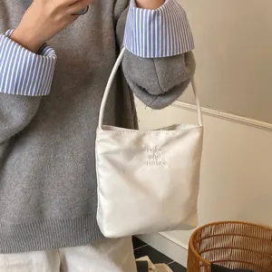 Bolso cubo blanco minimalista con bordado Hope and future sostenido por una modelo