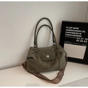 Detail of olive green pillow bag with wide geometric woven strap and leather handle