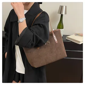 Detail of dark brown suede tote bag with metallic bow and long handles for women