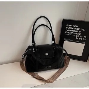 Detail of black Boston bag with silver buckle and colorful woven wide shoulder strap