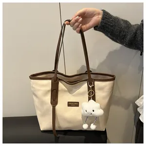 Detail of canvas tote bag with brown straps and cute cloud plush pendant accessory