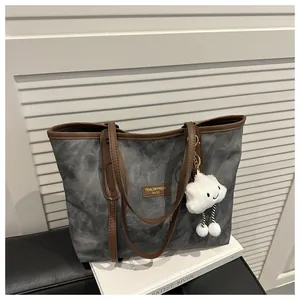 Detail of grey tie-dye canvas tote bag with brown leather straps and cloud charm accessory