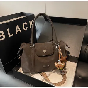 Detail of dark brown Boston bag with woven strap and bear charm in a premium gift box