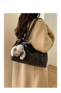 Détail d'un sac cabas rétro noir avec texture souple et breloque lapin en peluche