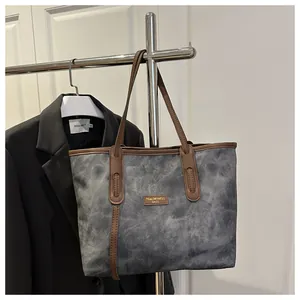 Detail of large tote bag with dark textured fabric and contrasting brown leather straps