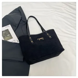Detail of black suede tote bag featuring a golden bow metal buckle and rivet hardware