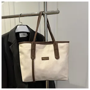 Detail of contrast stitching and brand label on a retro tote bag with brown handles