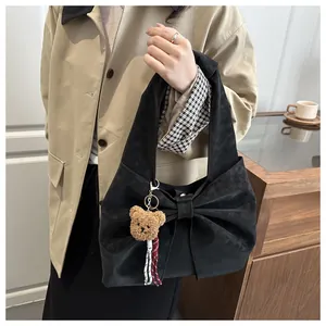 Detail of black bow shoulder bag with cute brown plush bear charm accessory