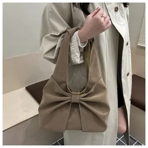 Detail shot of a beige shoulder bag featuring a large decorative bow and leather texture