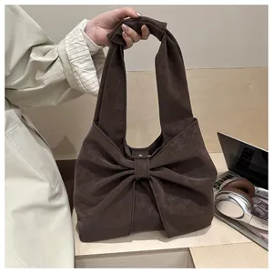 Detail of dark brown suede tote bag featuring a large bow and knotted handle design