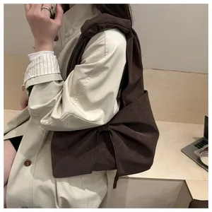 Detail of dark brown shoulder bag featuring a large bow knot and textured matte finish