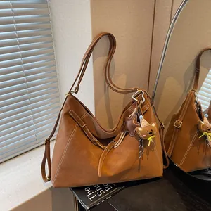 Brown suede Hobo shoulder bag with bear charm and adjustable strap in a bright room