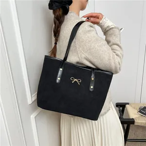Minimalist black suede tote bag for women featuring a delicate gold bow metal ornament
