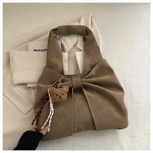 Detail of brown faux leather handbag with pleated bow design and plush bear charm