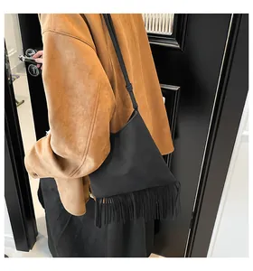 Détail d'un sac à main noir à franges porté par un mannequin en veste de daim marron