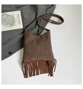 Gros plan détaillé d'un sac bandoulière en daim marron foncé avec franges et anse souple