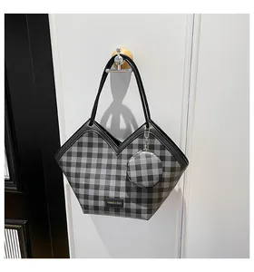 Detail view of plaid bucket bag featuring a unique V-shaped opening and a mini coin purse