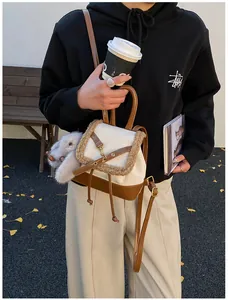 Detailed view of cream and brown backpack with fuzzy trim and a plush rabbit charm