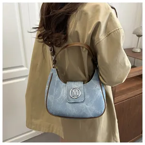Detail of light blue crescent bag with brown leather trim and M-logo buckle on model