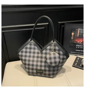 Close-up of checkered bucket bag with fashion logo plate and round coin purse charm