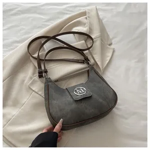 Detailed view of the crescent shoulder bag showing gray suede material and brown leather trim