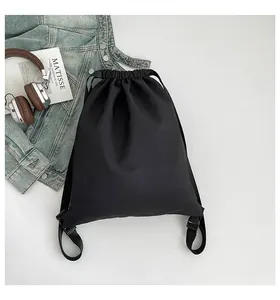 Flachbild eines schwarzen Nylon-Rucksacks mit Kunstbuch, Kopfhörern und Jeansjacke