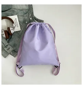 Flachbild eines lavendelfarbenen Kordelzug-Rucksacks mit Kopfhörern und Kunstbuch-Dekor
