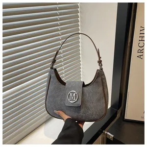 Macro detail of crescent bag showing grey textured fabric and silver M-shaped metal buckle