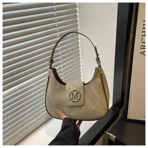 Detail of green suede crescent bag featuring a round silver metal buckle with M logo