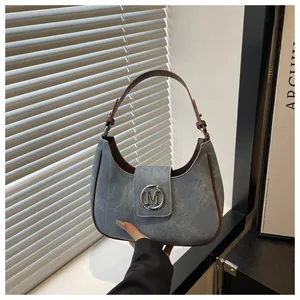 Detail of blue crescent bag featuring silver M-logo buckle and brown leather handle