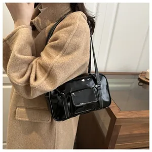 Detail of black patent leather handbag with white contrast stitching and front pocket