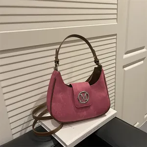 Pink crescent hobo bag with brown leather trim and silver M logo on a leather seat
