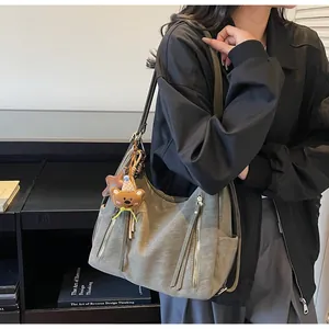Détail d'un sac cabas rétro gris avec fermetures éclair décoratives et breloques ours