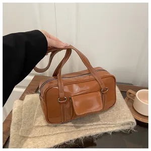 Detail of retro brown leather handbag featuring white contrast stitching and silver hardware