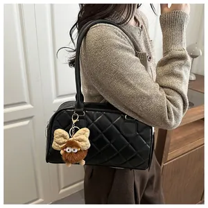 Detail of black quilted shoulder bag featuring a cute brown plush doll charm