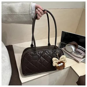 Close-up of brown quilted bowling bag with plush monster charm and sleek PU leather texture