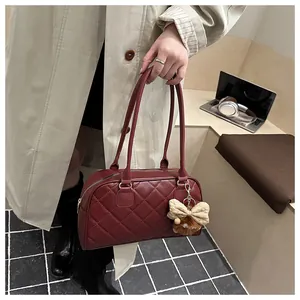 Close-up of wine red quilted bowling bag with a cute bear charm on a trench coat