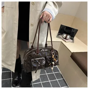 Close-up of dark brown patent leather handbag with bow pockets and wooden bead charm