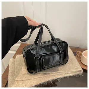 Detail of black patent leather bag with white stitching and adjustable long shoulder strap