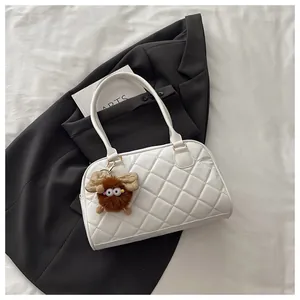 Detail of white quilted bowling bag with plush charm and slim shoulder straps