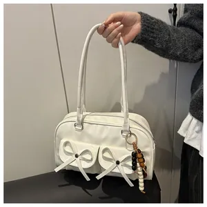Macro view of white bowling bag featuring bow-tie pockets and beaded pendant detail