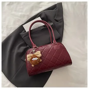 Detail of burgundy quilted leather bowling bag with a cute plush charm accessory