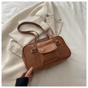 Detail of caramel leather bag with white contrast stitching and exterior flap pocket