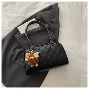 Detailed view of black quilted bowling bag with a cute plush bear charm on a blazer