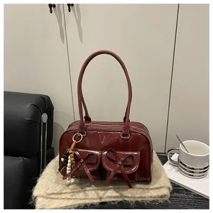 Close-up of deep red patent leather bowling bag featuring decorative bows and beaded charm