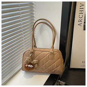 Close-up of quilted light brown shoulder bag with a cute plush monster charm