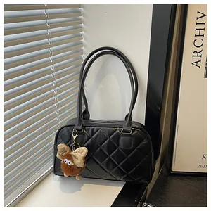 Detail of black quilted bowling bag featuring large diamond stitching and plush charm