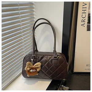 Close-up of brown quilted bowling bag with long handles and a cute plush monster charm